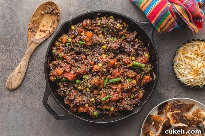 Cooked quinoa, veggies and beans mixed together in a skillet.