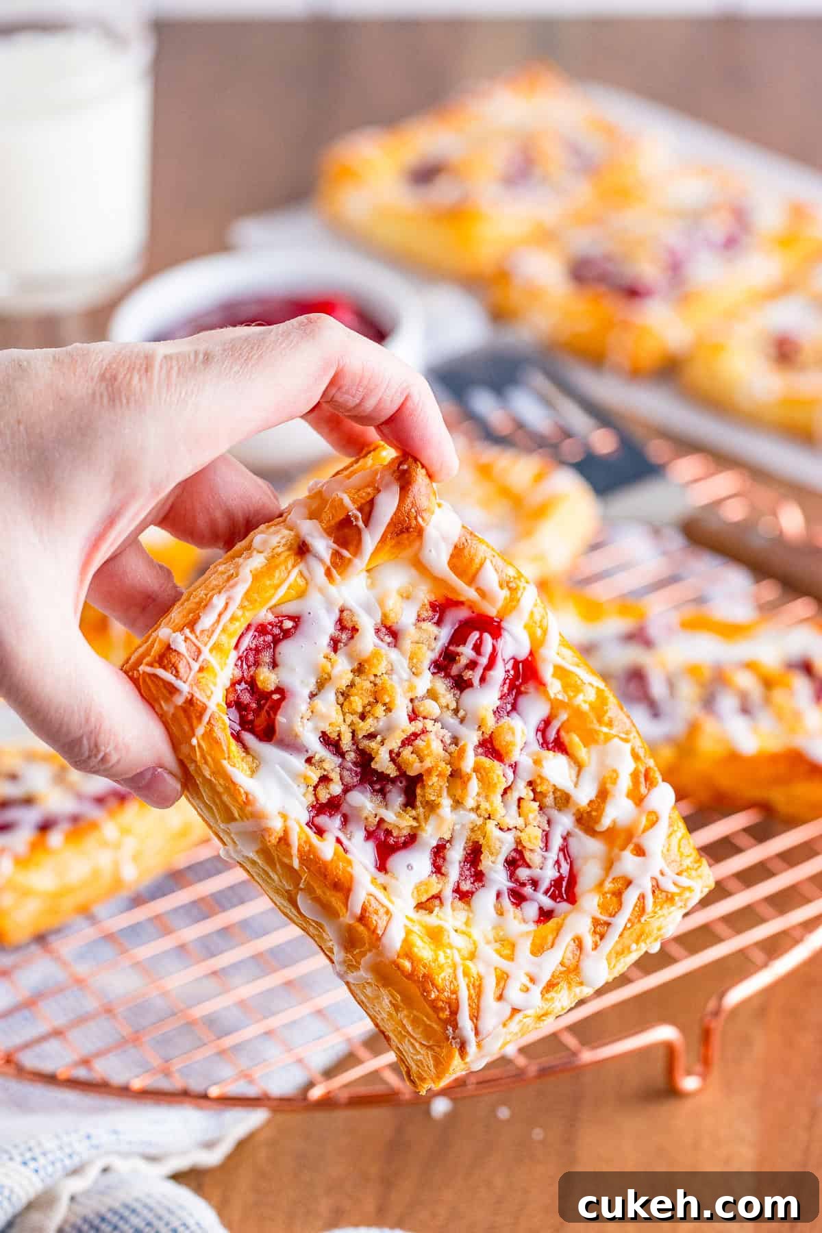 Cherry Danish with Cream Cheese: Flaky Pastry Recipe 6 Hand holding up one Cherry Danish.