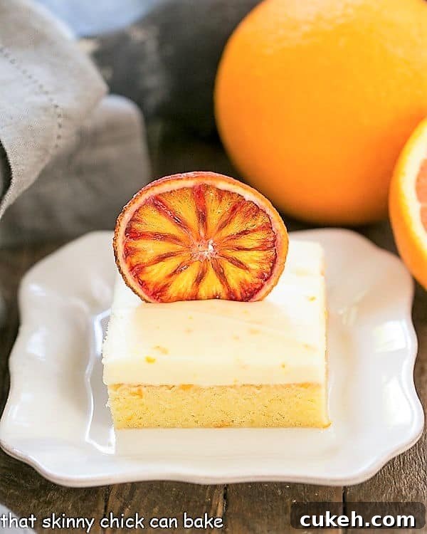 Orange Cake with Cream Cheese Frosting on a square white plate with oranges