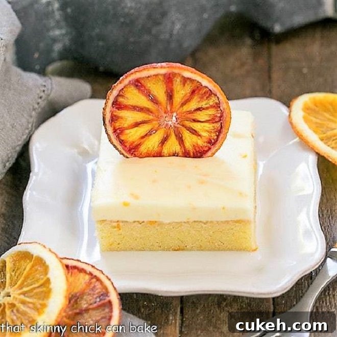 Orange Cake with Cream Cheese Frosting on a square white plate with dried orange slices
