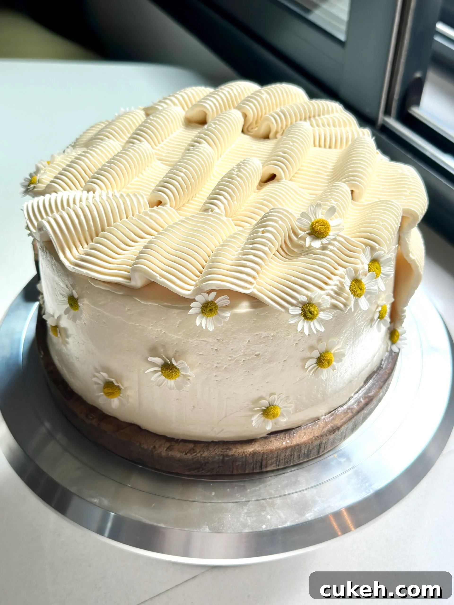 Frosted two layer banana cake with rippled frosting and edible flowers.