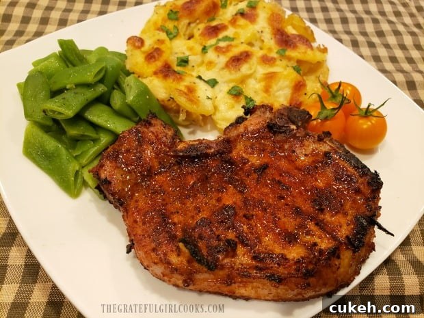 A plate with a pork chop, green beans, tomatoes and Scalloped Potatoes For Two. A plate with a pork chop, green beans, tomatoes and Scalloped Potatoes For Two.