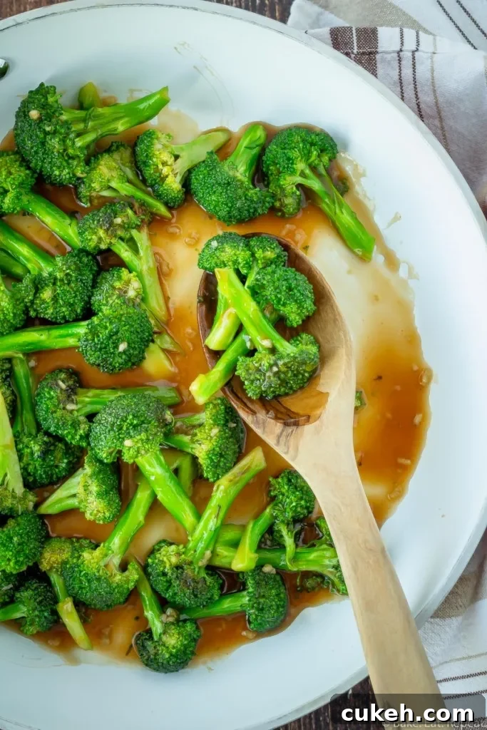 10 minute Asian broccoli stir fry in a skillet with a spoon.