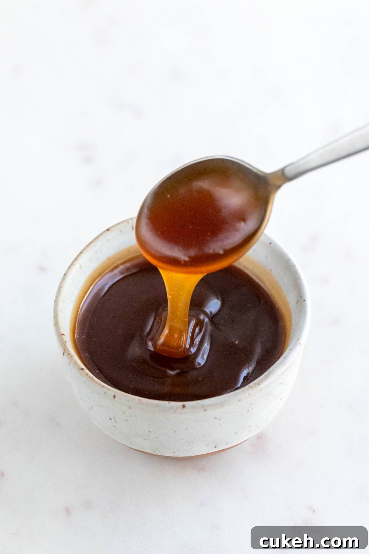 Spoon dipping into vegan caramel sauce bowl.