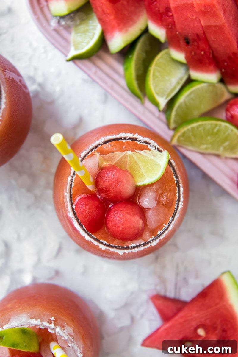 Watermelon Mango Margaritas overhead shot of watermelon mango margarita with yellow straw with watermelon balls and lime wedges garnished on the side