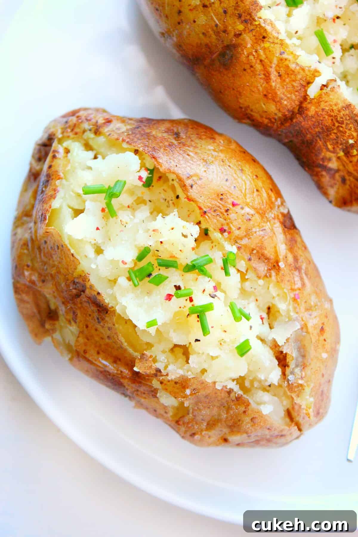 Microwave Baked Potatoes Sliced baked potato on a plate.