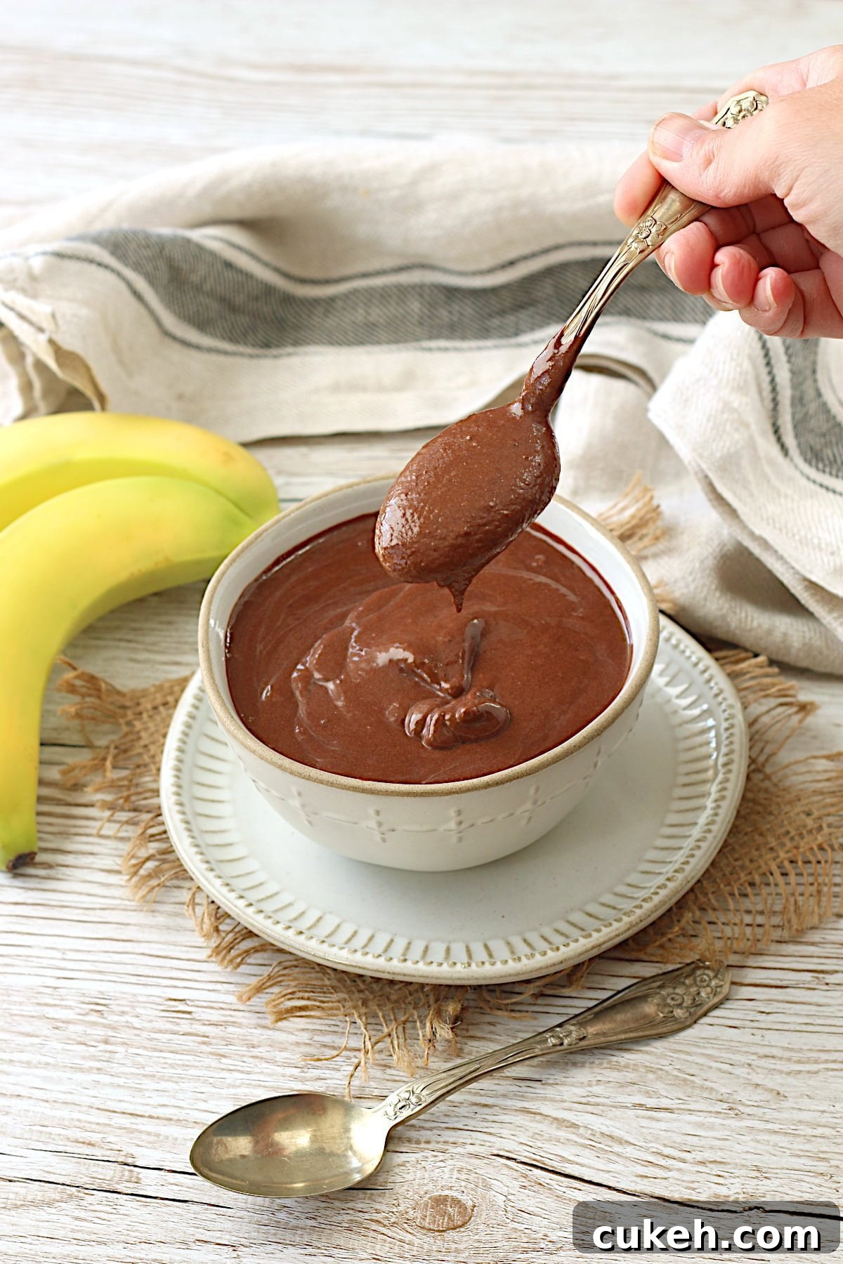 A spoonful of vegan chocolate banana pudding being scooped from a white bowl.