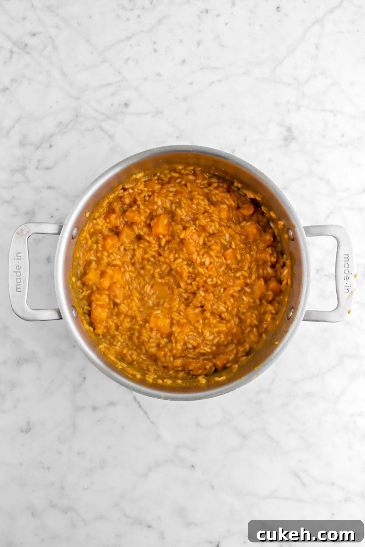 butternut squash risotto in large pot on marble surface.