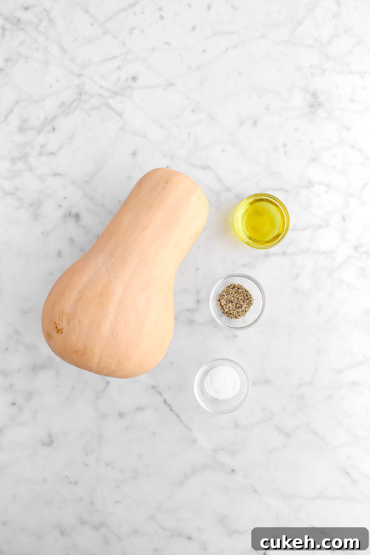 butternut squash, olive oil, ground pepper, and salt on marble surface.