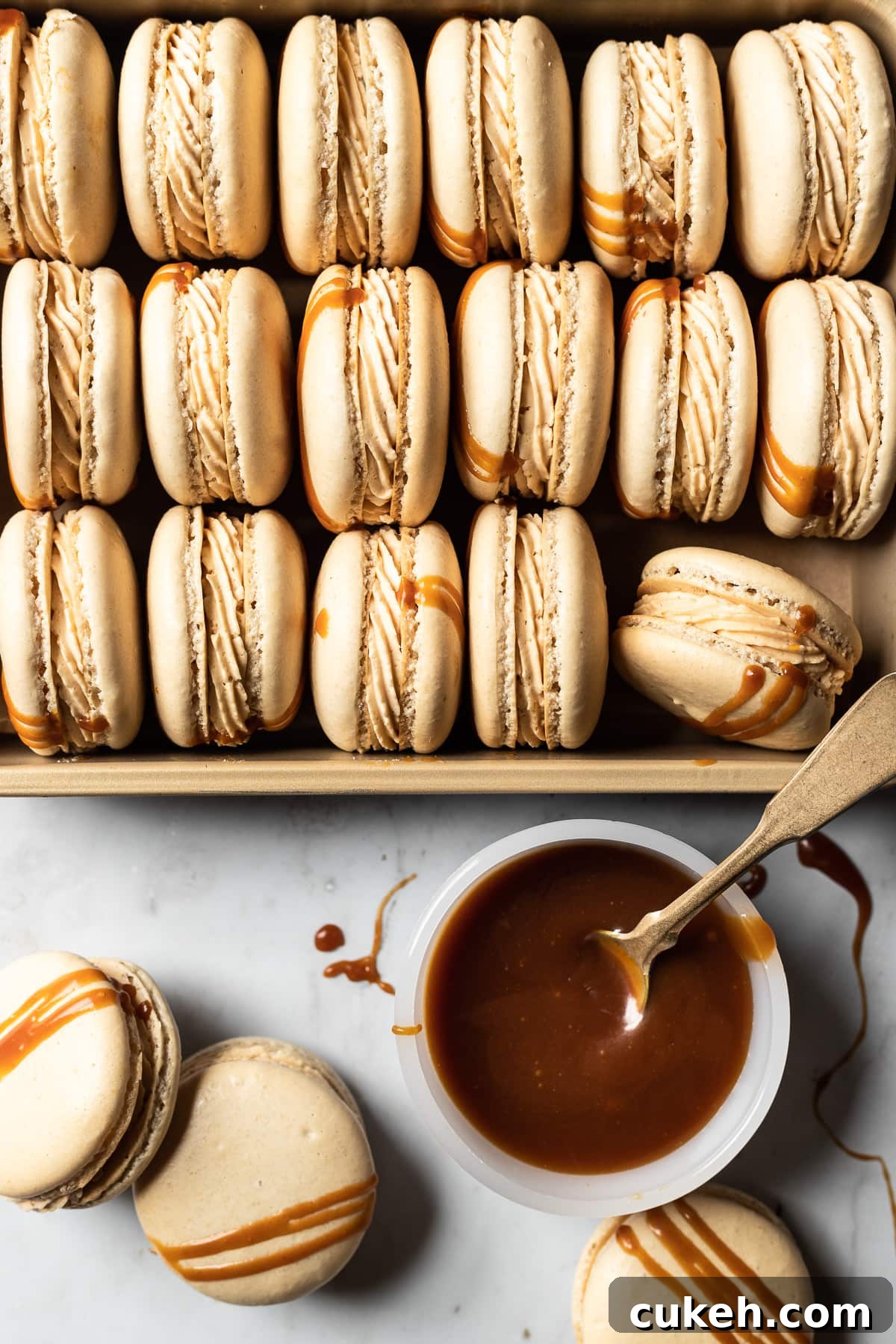Three rows of salted caramel macarons turned on their sides in a gold pan. 