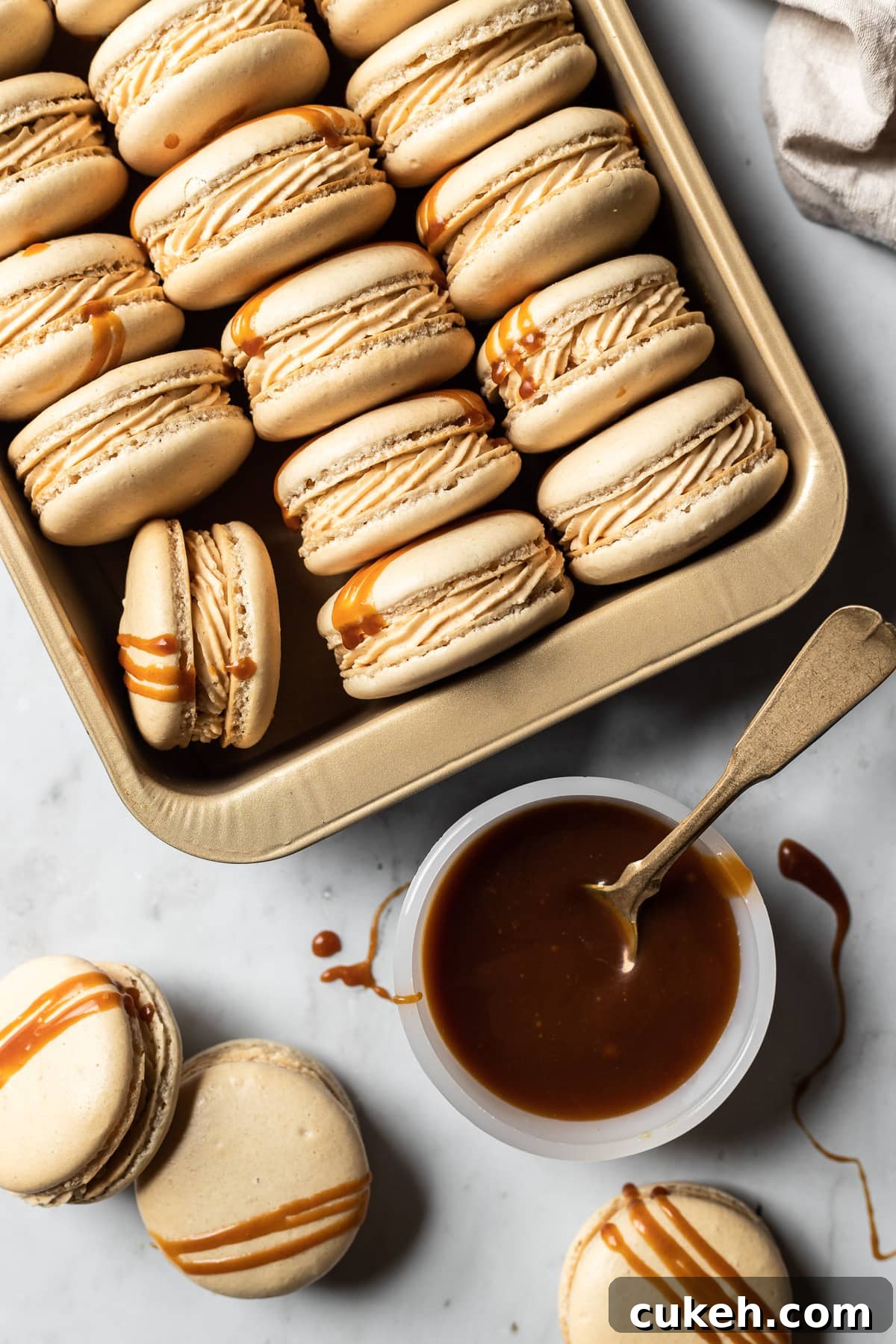Macarons in a gold metal pan with a bowl of salted caramel.