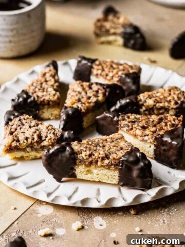 Nussecken bars dipped in chocolate on a white fluted plate.