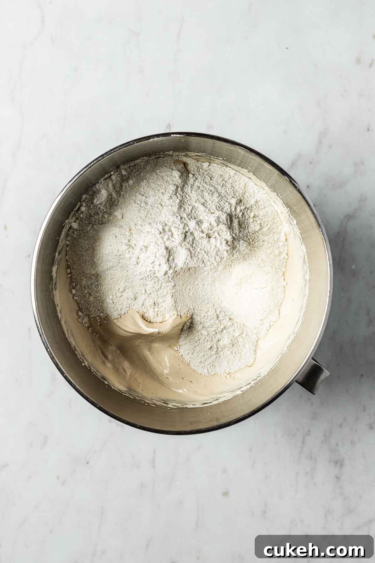 Almond flour and powdered sugar in a mixing bowl on top of brown sugar meringue.