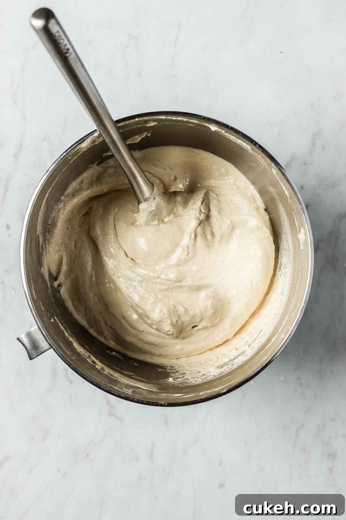 A mixing bowl of almond flour and powdered sugar being folded into meringue.