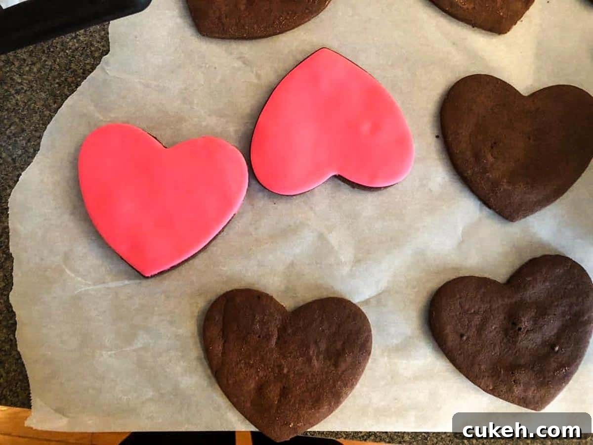 chocolate heart cookies being covered in pink fondant heart shapes