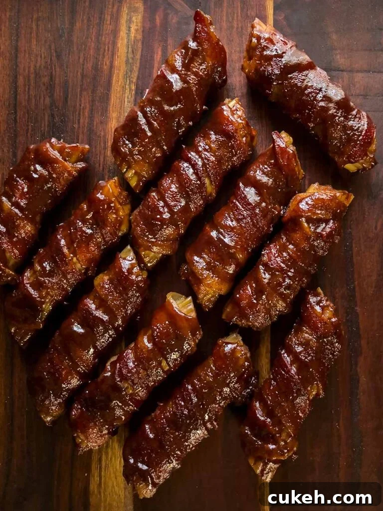Smoked Shotgun Shells: Savory Sausage-Stuffed Appetizer Recipe 9 Smoked shotgun shells on a brown cutting board.