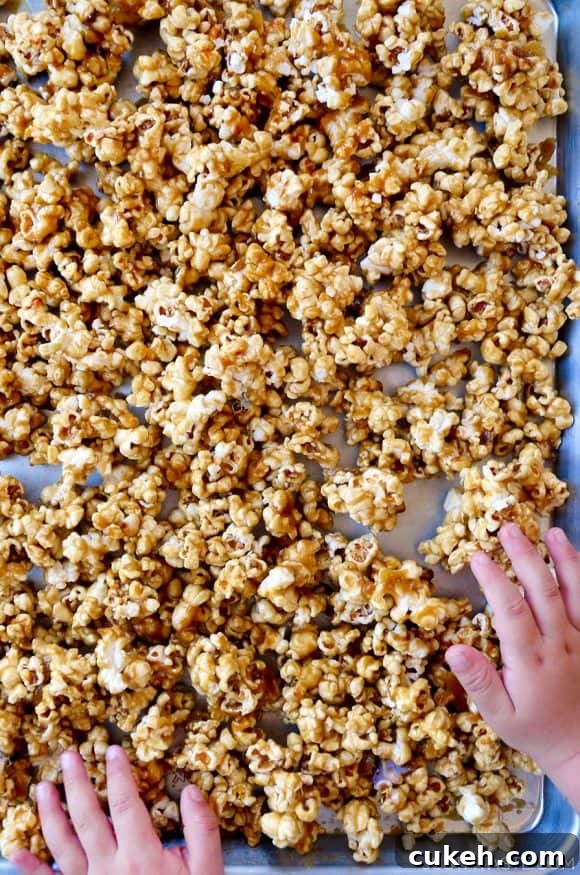 Homemade Caramel Corn Recipe for Perfect Crunch 5 Child's hands on baking sheet of homemade caramel corn