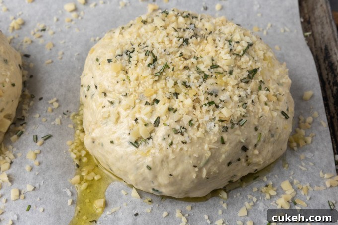 Unbaked Rosemary Parmesan Garlic Bread on a parchment lined sheet pan