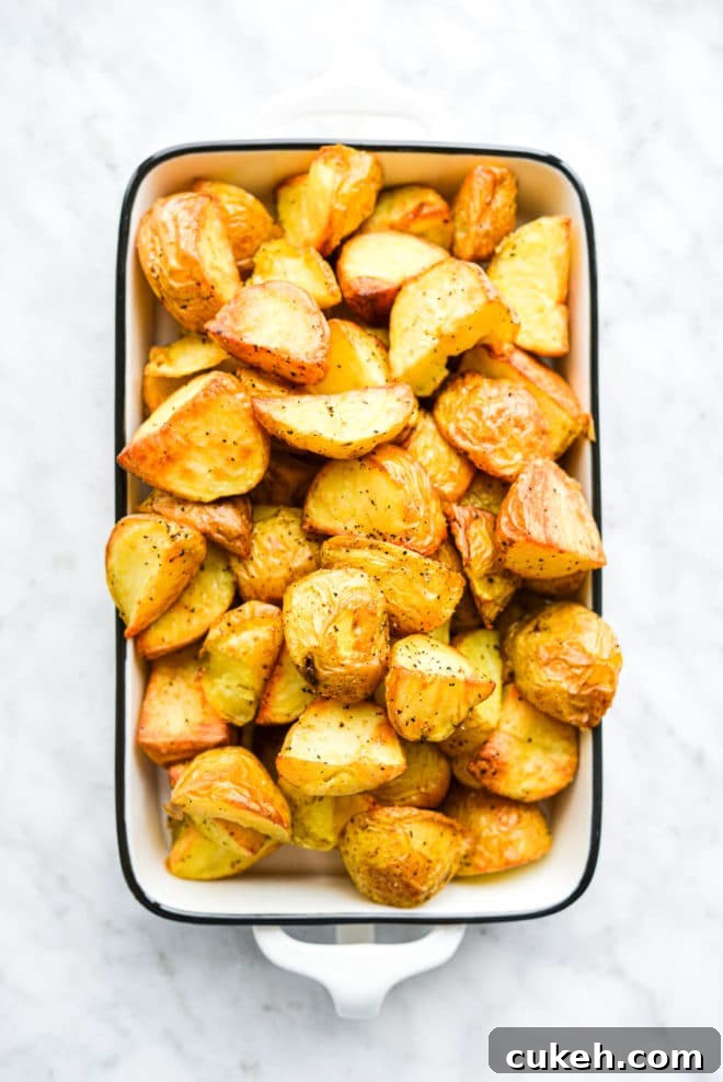 a small dish filled with crispy roasted potatoes sitting on a marble surface