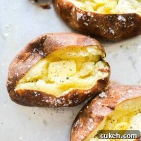 4 split open baked potatoes with butter, salt, and pepper in each of them