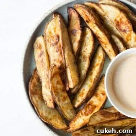 a plate of crispy roasted potato wedges next to a creamy sauce