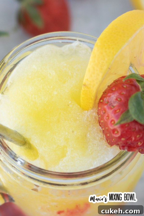 Closeup shot of frozen strawberry lemonade with strawberry and lemon garnish.