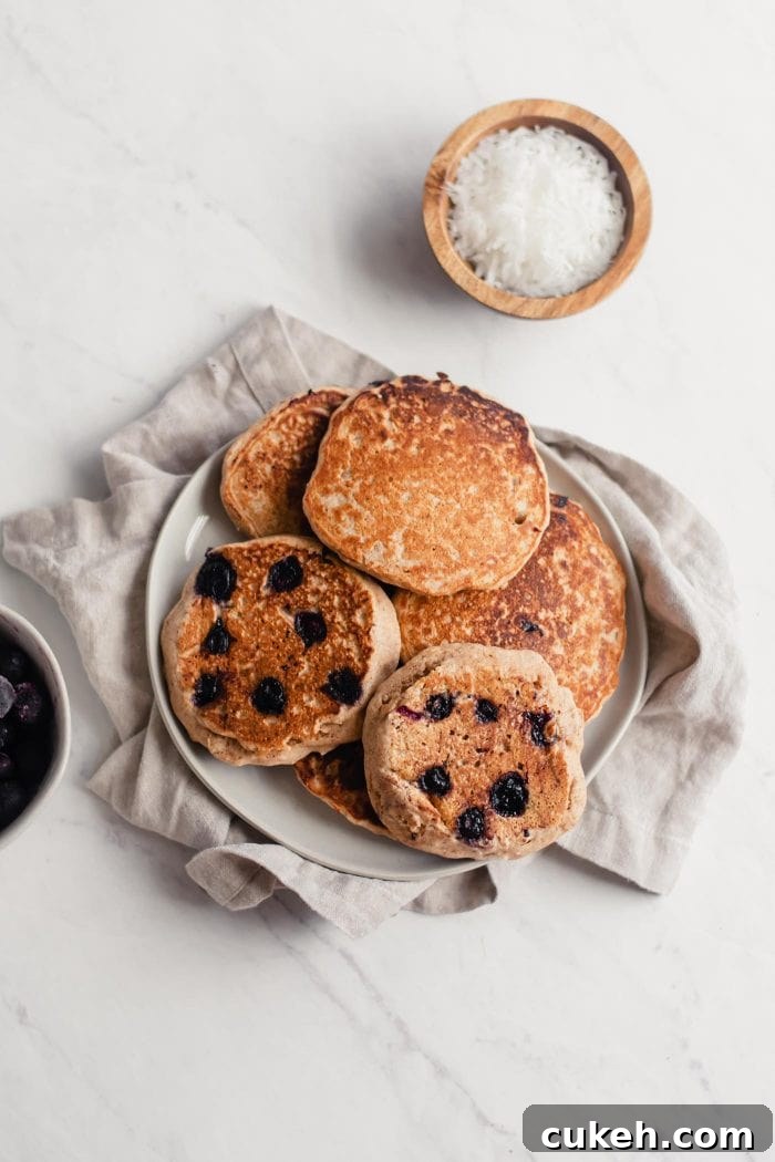 Pile of blueberry coconut pancakes on a plate.