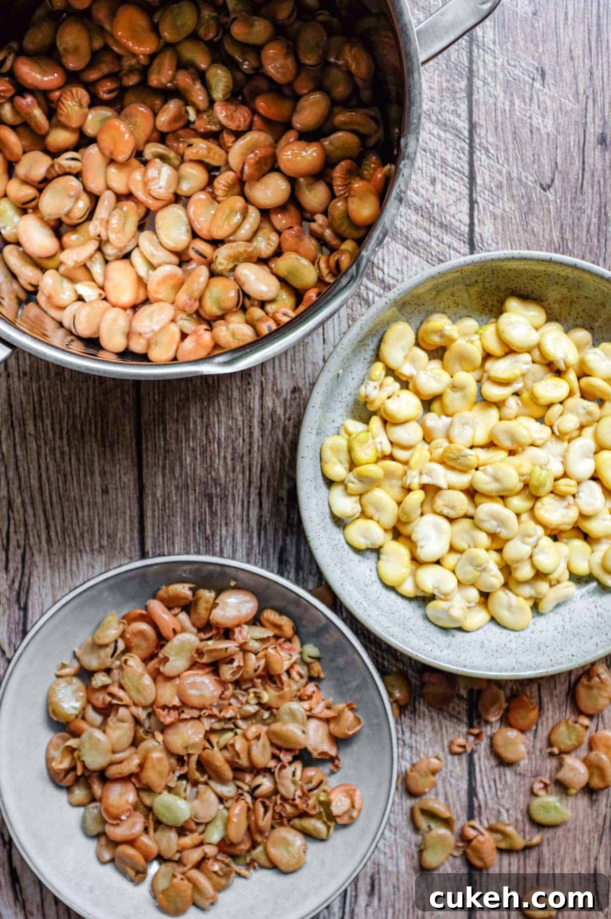 Three bowls, the top one containing soaked fava beans the middle skinned fava beans and the bottom bowl the skins of the beans.