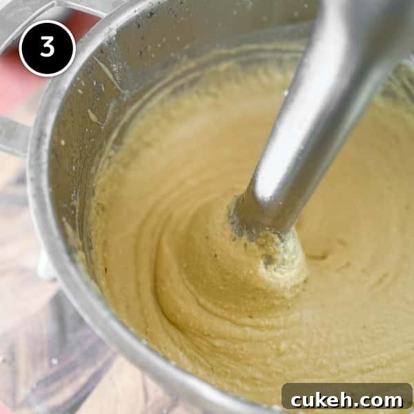 An immersion blender making a puree from cooked fava beans.