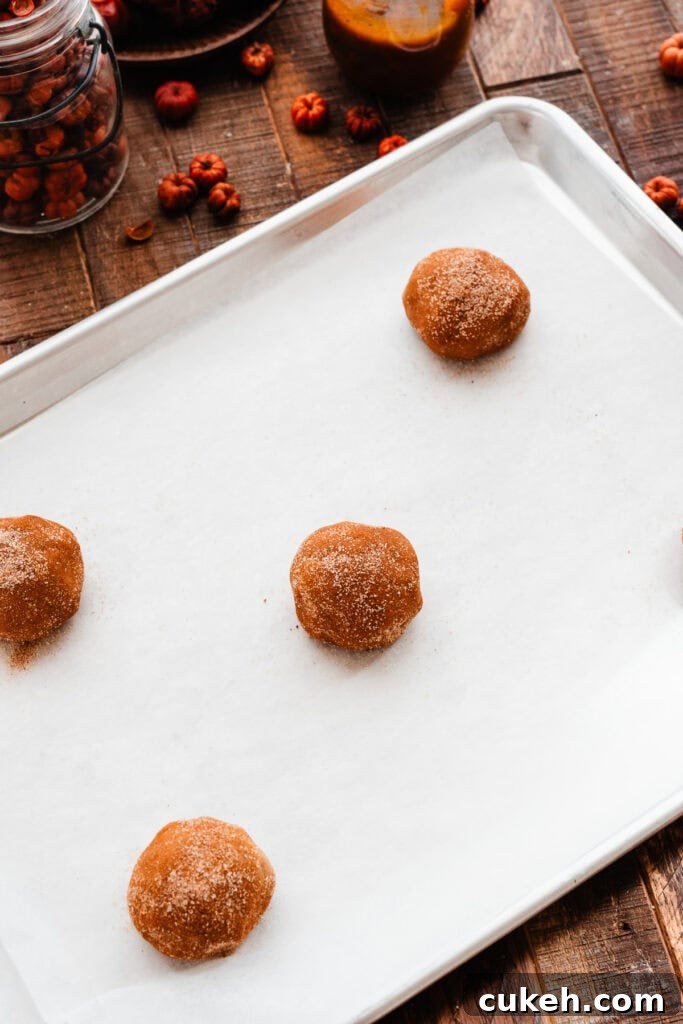 Cookie dough balls spread out on a pan, ready for the oven.