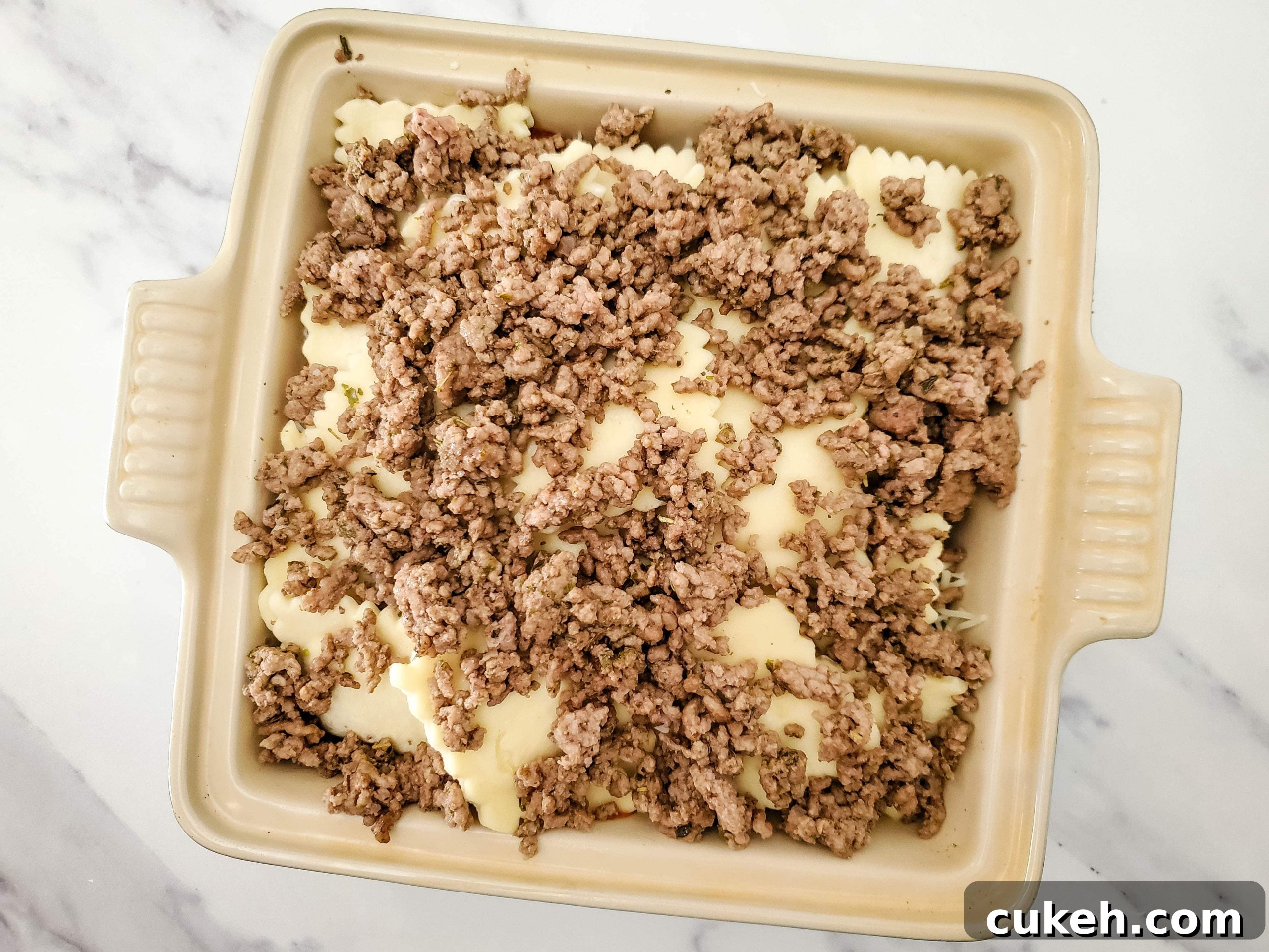 Neutral colored baking dish with frozen ravioli lasagna layers