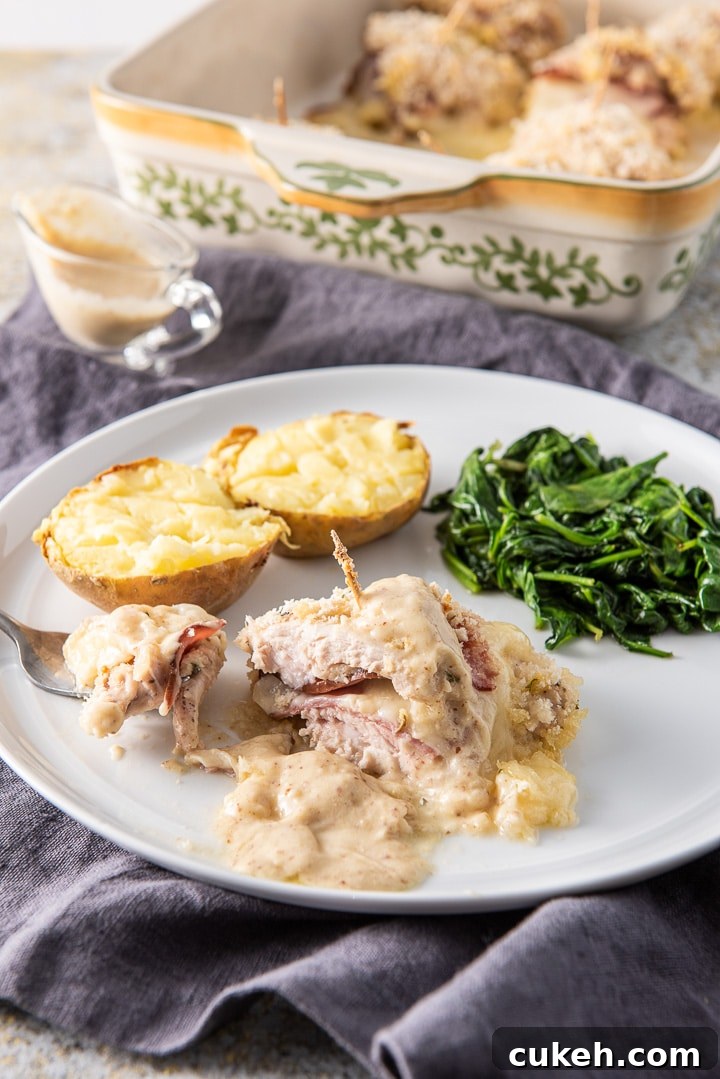 Crispy Baked Chicken Cordon Bleu Recipe for Weeknight Dinners 10 Bite of the chicken on a fork with a potato and spinach on the side