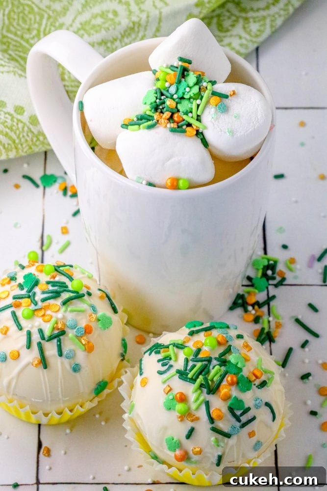 Saint Patrick's Day Hot Chocolate Bombs Recipe: Festive Ideas & Tips 2 white chocolate hot chocolate bombs covered in Saint Patricks Day sprinkles on a table next to a mug with marshmallows and green and gold sprinkles in it