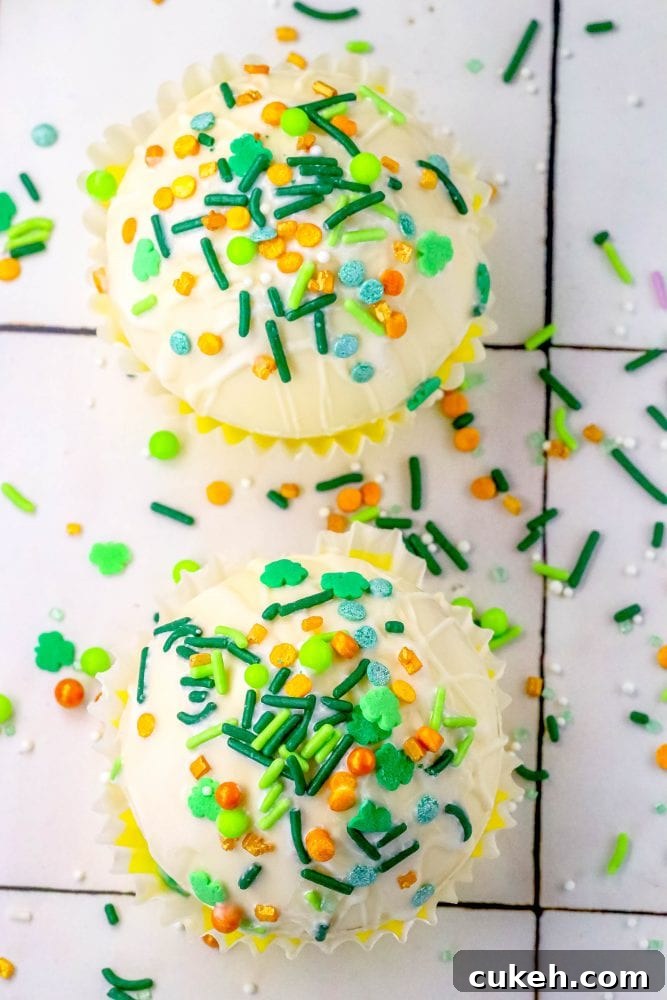 Saint Patrick's Day Hot Chocolate Bombs Recipe: Festive Ideas & Tips 5 white chocolate hot chocolate bombs covered in saint patricks day sprinkles on a table next to a mug with marshmallows and green and gold sprinkles in it