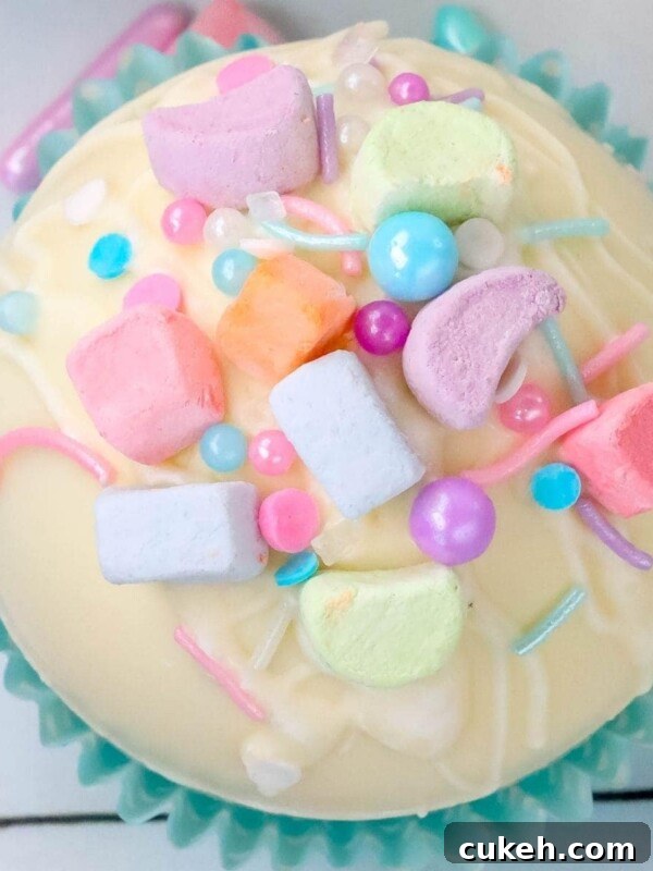 Saint Patrick's Day Hot Chocolate Bombs Recipe: Festive Ideas & Tips 9 white chocolate hot chocolate bomb in a blue cupcake wrapper with lucky charms marshmallows and sprinkles on top next to a mug