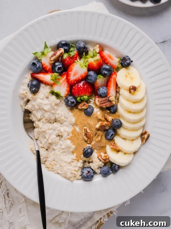 Protein oatmeal in a small white bowl, topped with berried, banana, and nut butter.