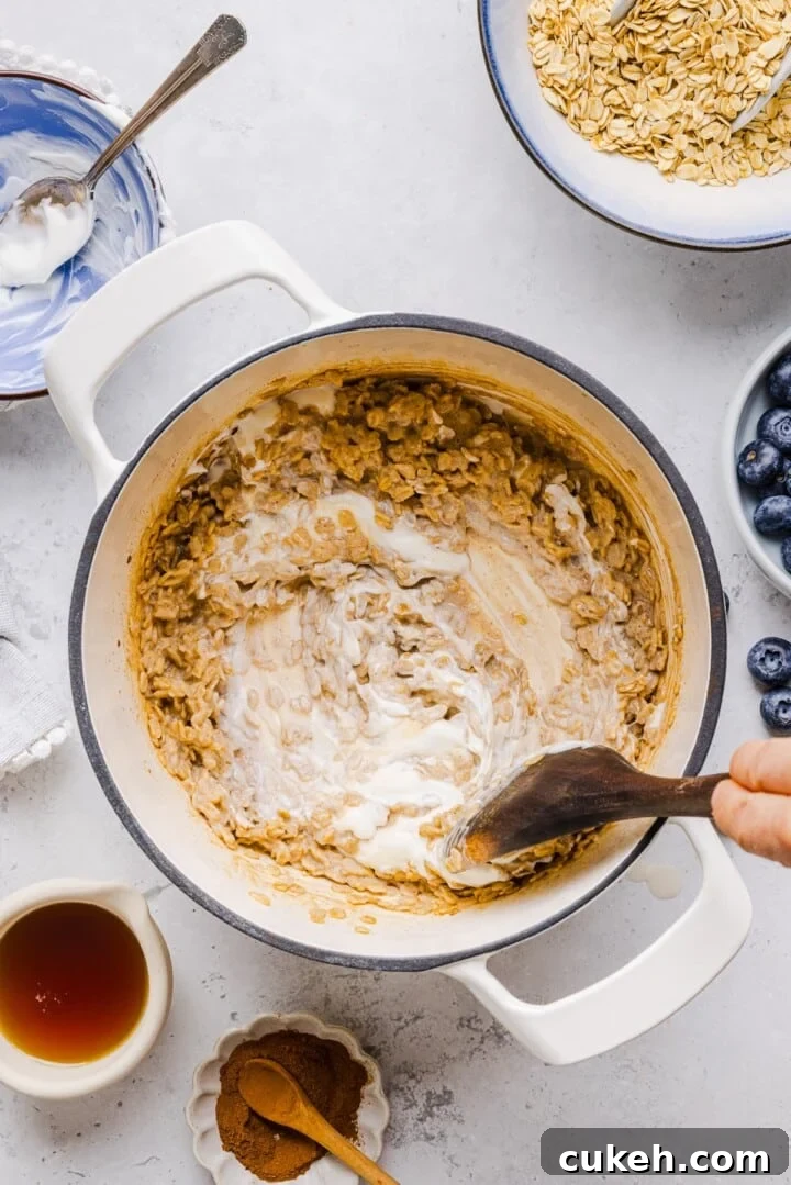 Greek yogurt being stirred into stovetop oatmeal.