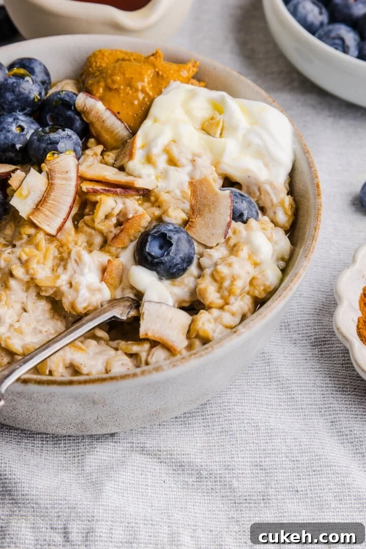 Close-up bowl of oatmeal with berries, coconut flakes, and greek yogurt.