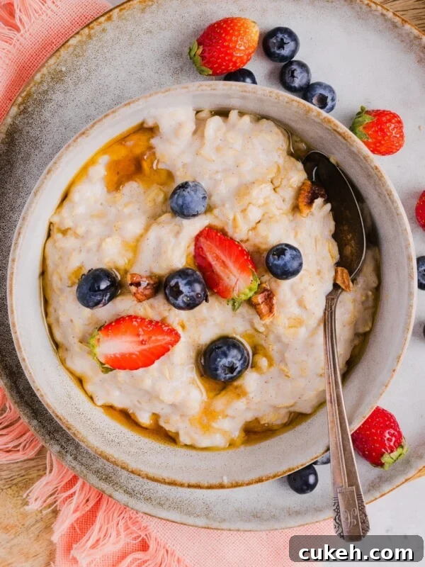 Overhead photo of egg white oatmeal in a bowl, with fresh berries and maple syrup