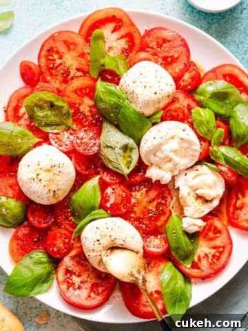 caprese salad with burrata cheese balls and bread on the side.