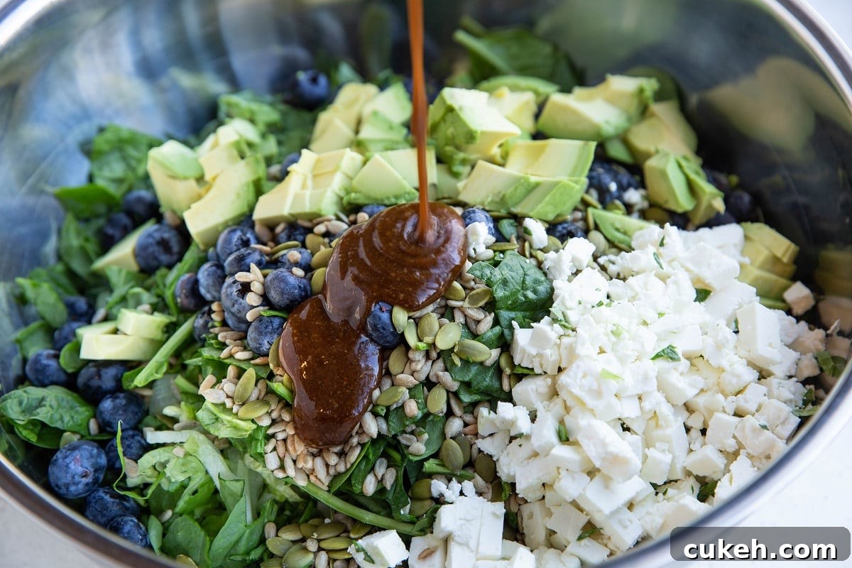 Drizzling balsamic vinaigrette into the bowl with the salad ingredients.