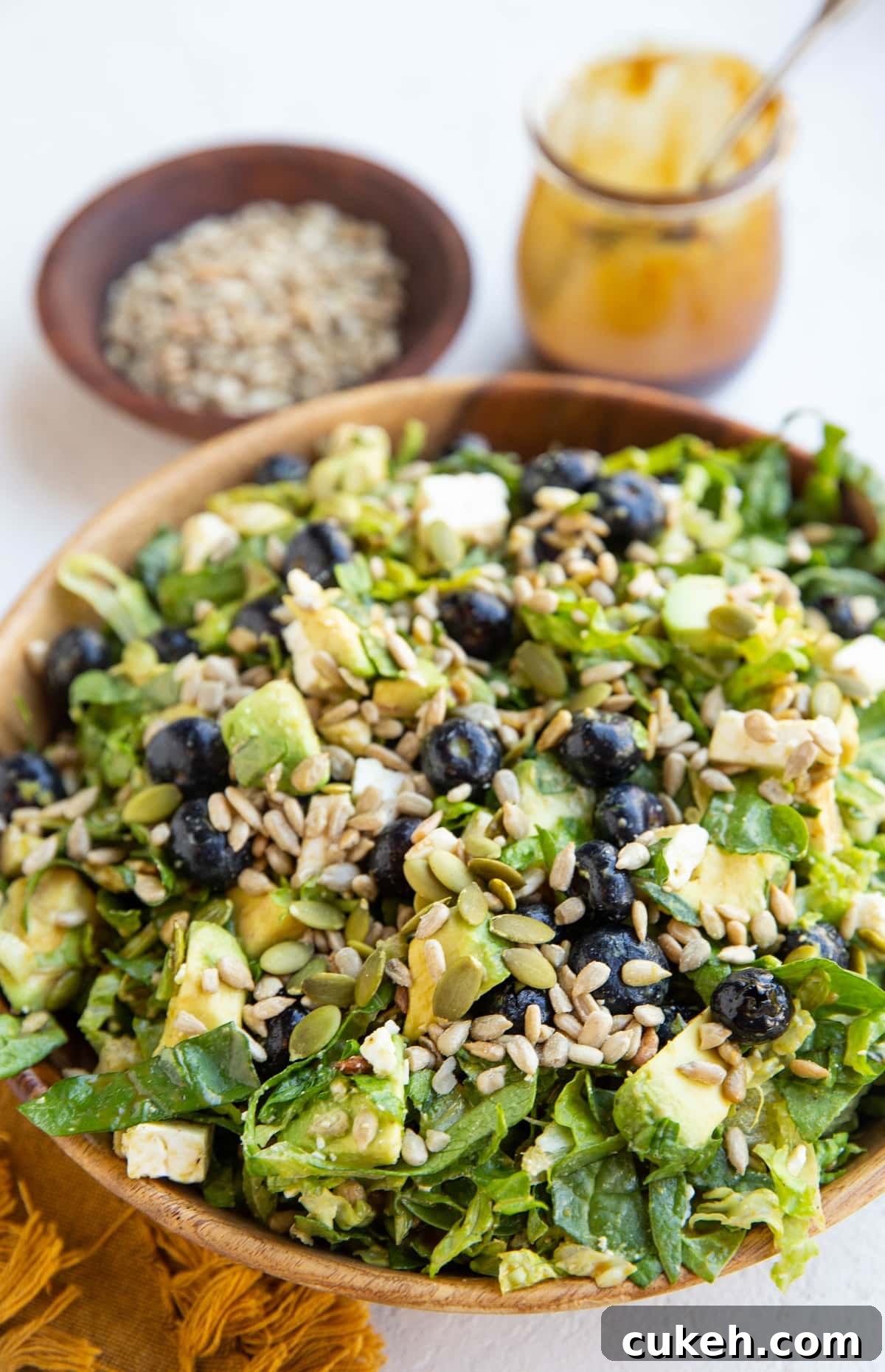 Big bowl of salad with salad dressing in the background.