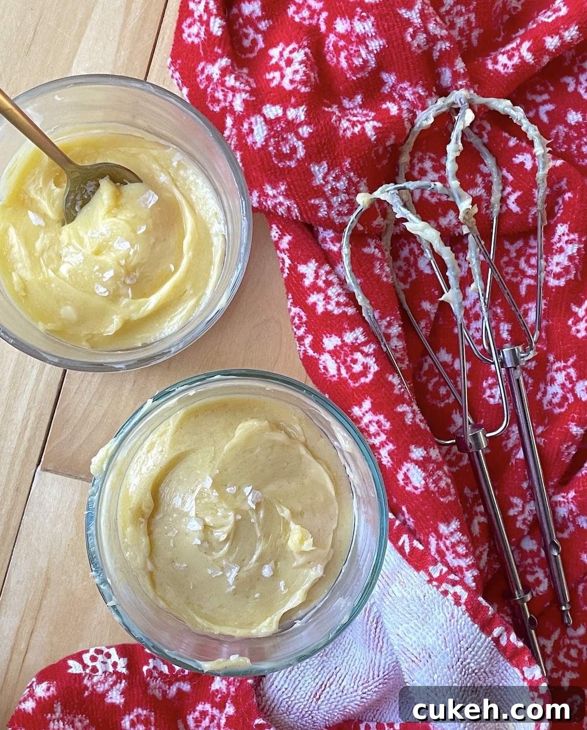 Two small bowls of honey butter next to two beaters with a red towel.