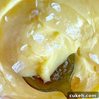 A spoon dipping into a bowl of honey butter.