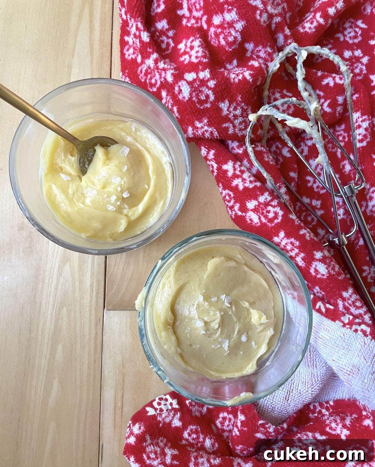 Two small bowls of honey butter next to two beaters with a red towel.