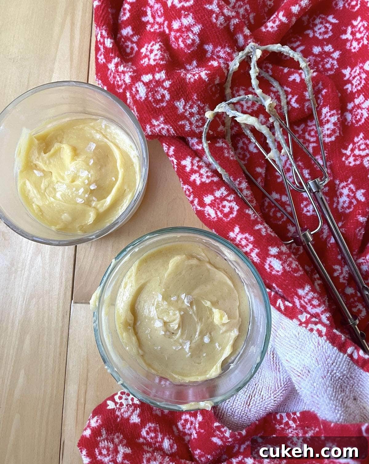 Two small bowls of honey butter next to two beaters with a red towel.