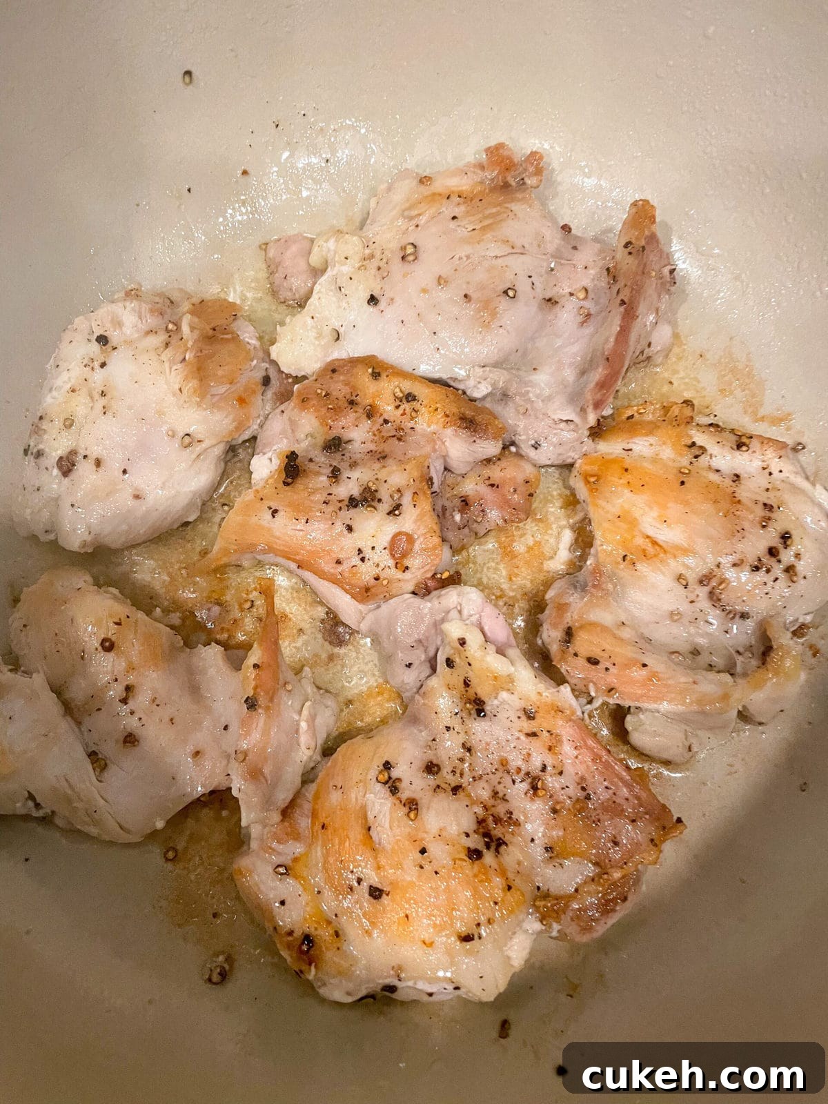 overhead shot of seared chicken thighs in dutch oven