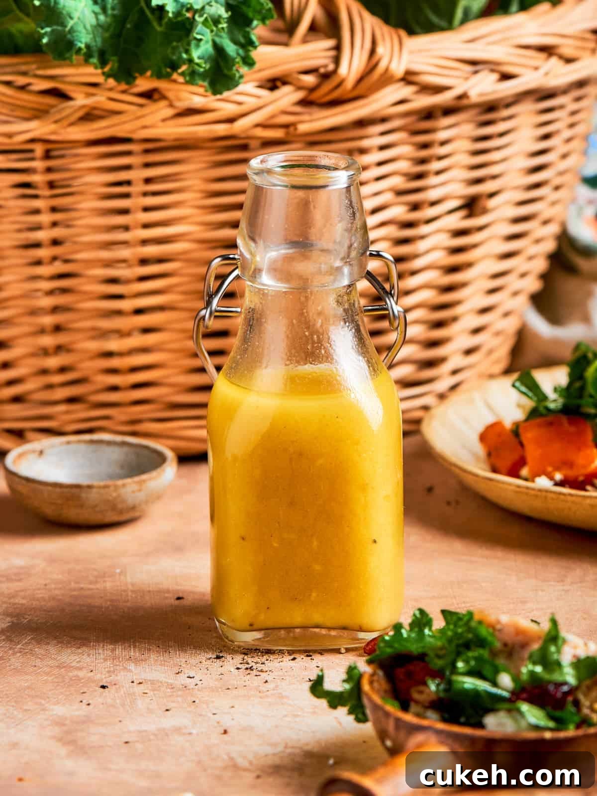 Bottle of homemade champagne vinaigrette standing in front of a woven kitchen basket.