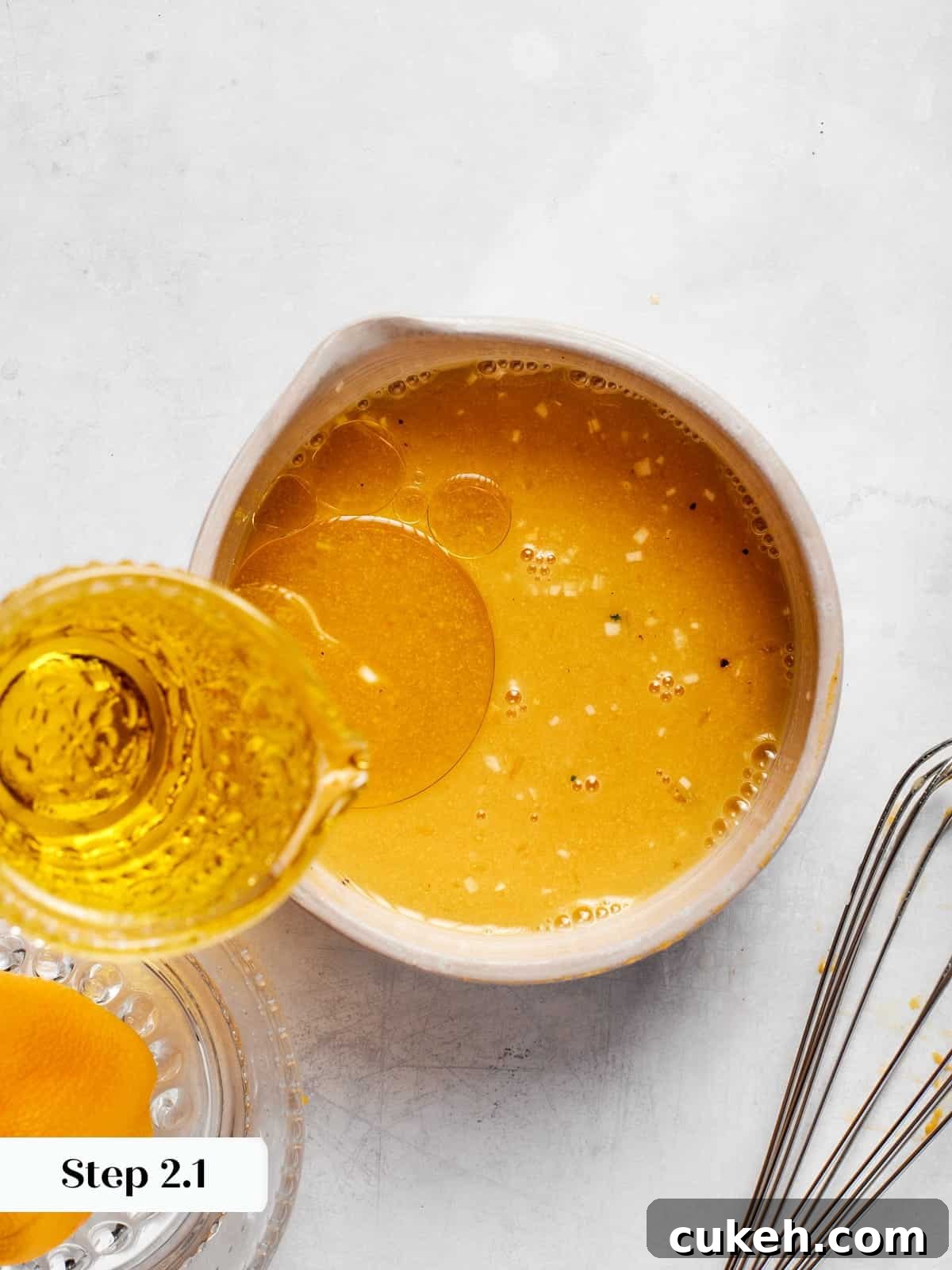 Olive oil slowly poured into champagne vinaigrette while whisking to combine.