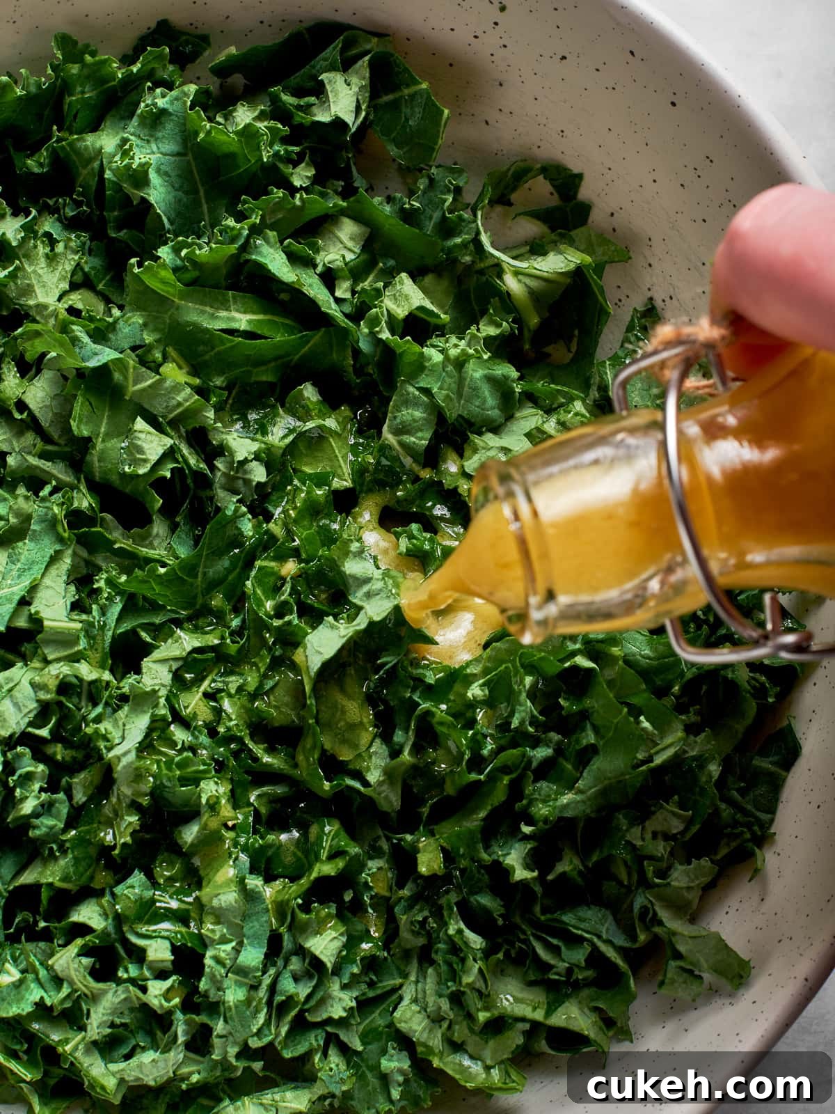 Champagne vinaigrette poured over kale salad greens in a large serving bowl.